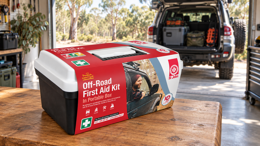 St John Off-Road Portable First Aid Kit on a wooden garage workbench with a touring 4WD behind it.