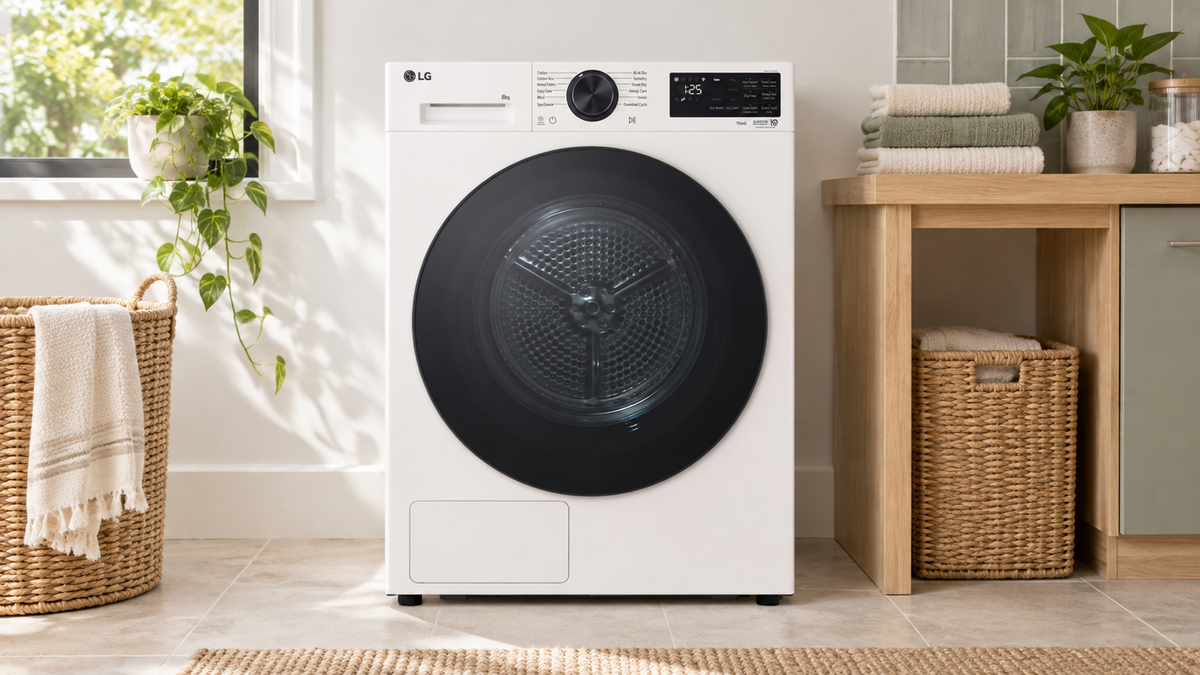 White LG DXH3-08W heat-pump dryer in a bright laundry beside an oak counter and folded towels.