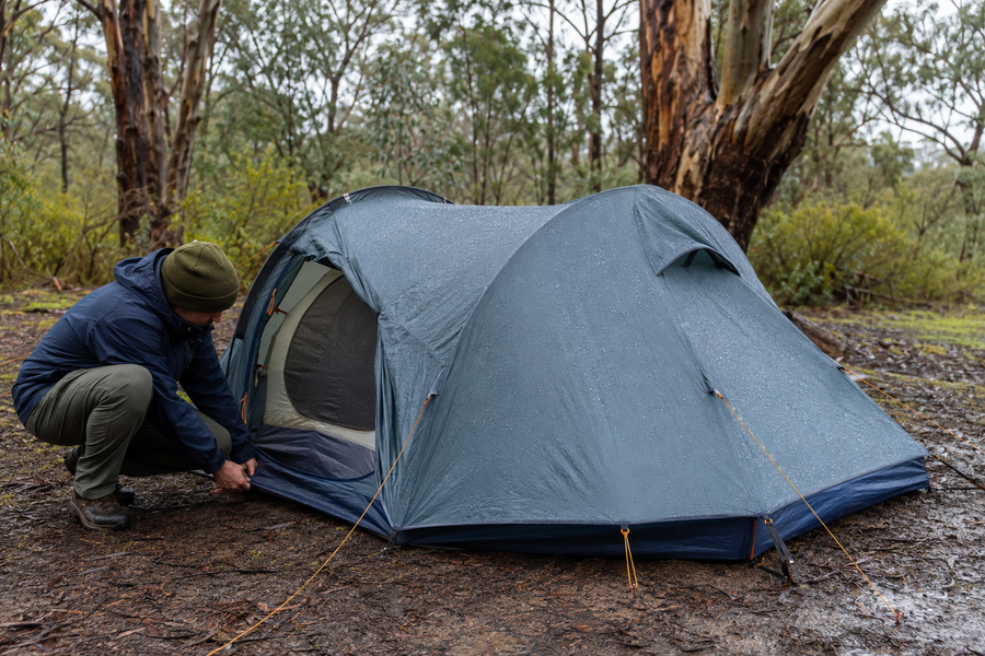 Camper inspecting a wet tent after overnight rain